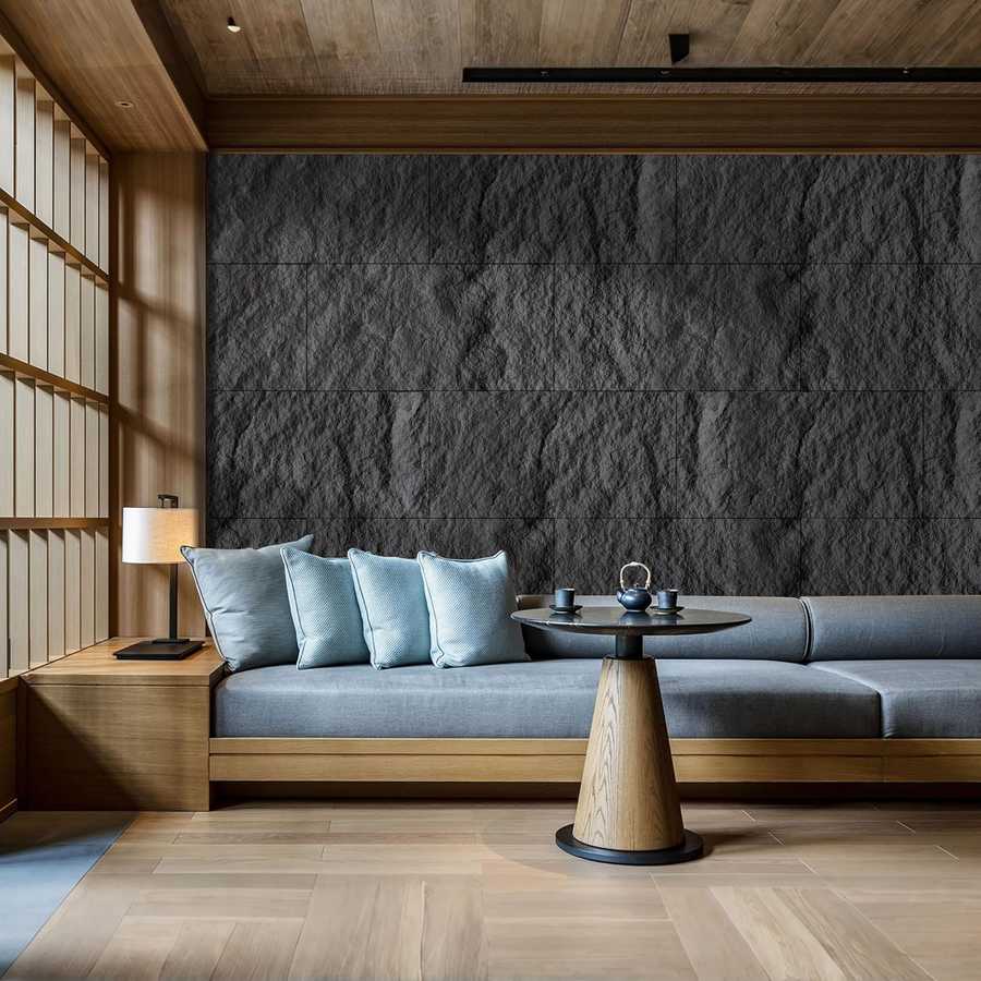 Dark textured 3D faux stone wall panels behind a blue sofa