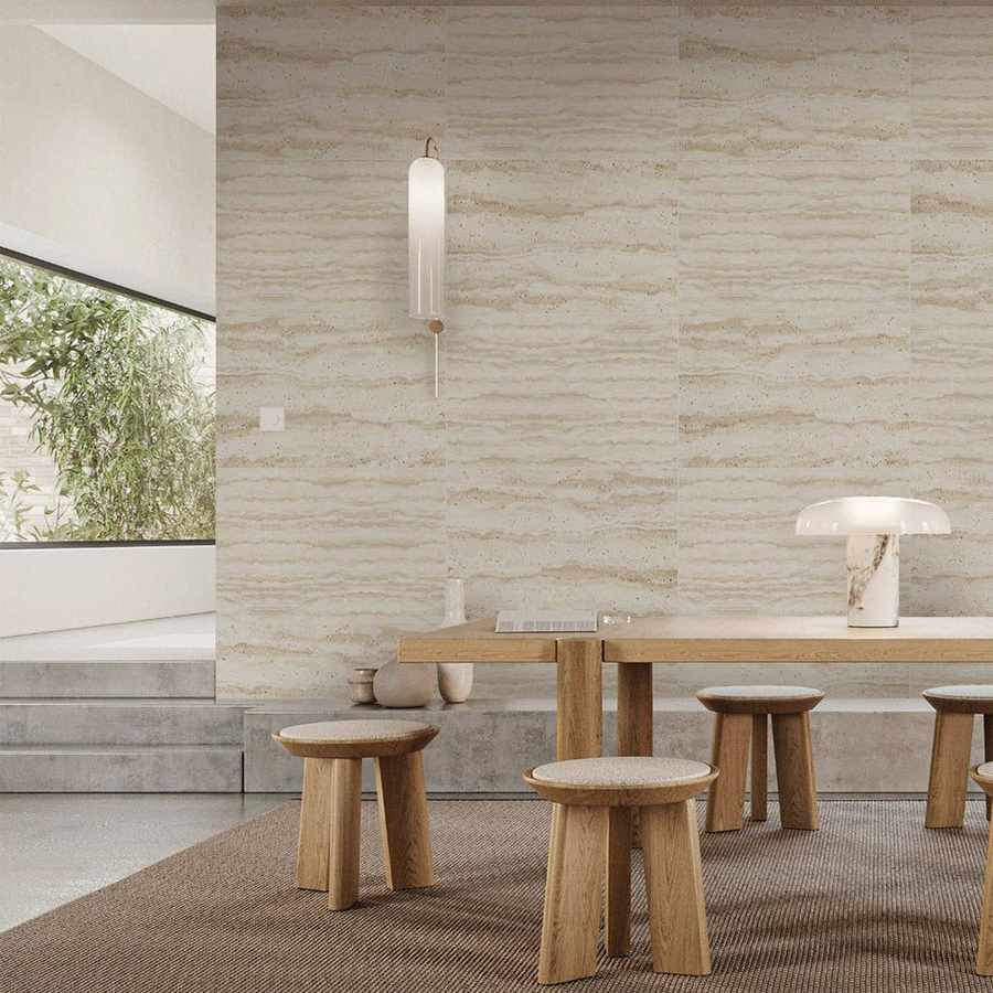 Travertine-style flexible stone wall panels behind a dining table and stools